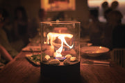 Planika Chantico Glassfire bioethanol tafelhaard met zwart stalen basis en glazen cilinder – moderne en compacte designhaard.