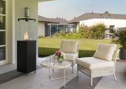 De Faro Buitenhaard in een groene tuin, omringd door planten en perfect voor gezellige buitenmomenten.