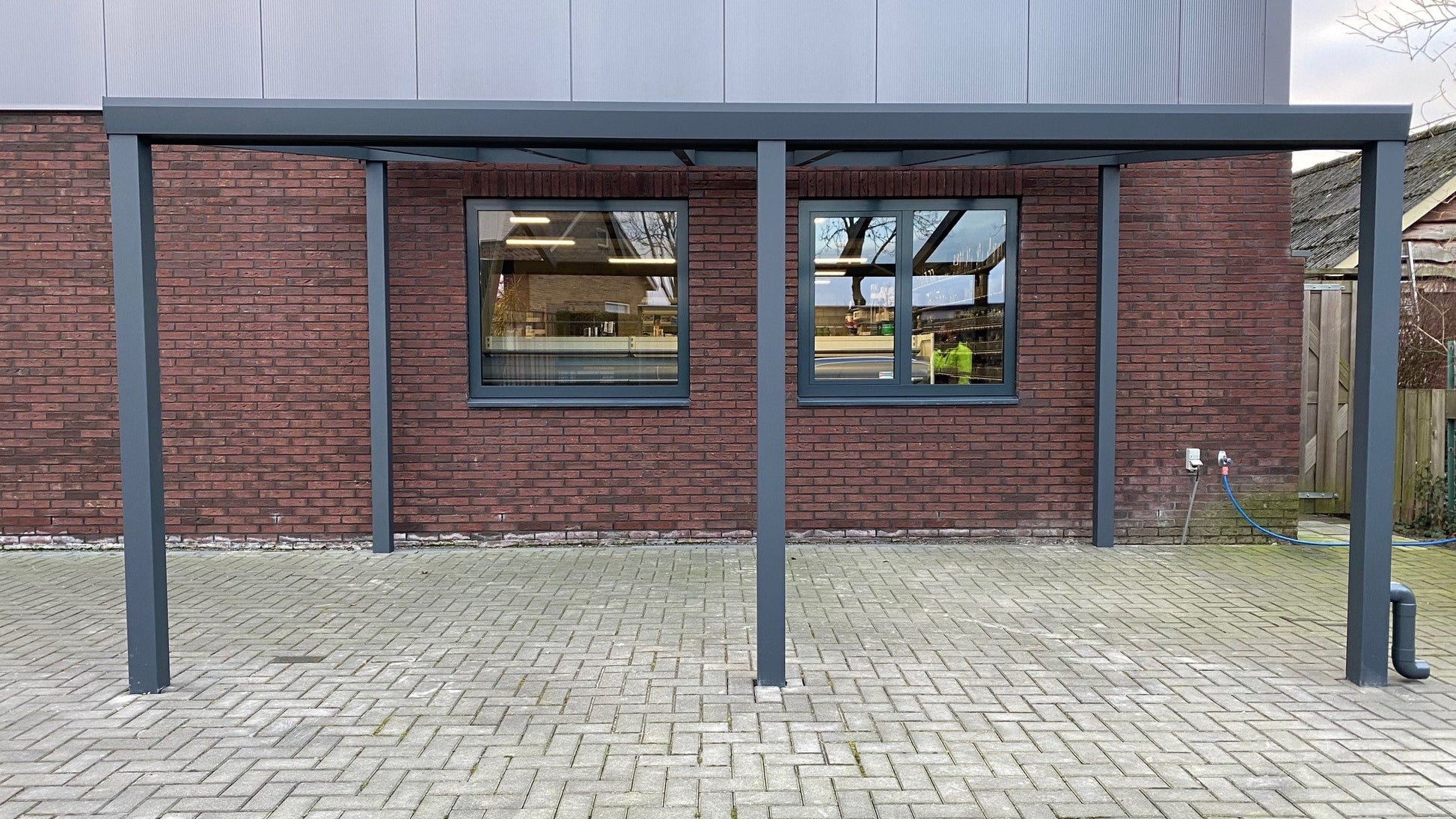 Een stijlvolle aluminium overkapping gezien vanaf de voorkant. Het strakke, moderne design past perfect bij elke tuin en biedt een ruime, beschutte buitenruimte.