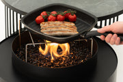 Moon design vuurtafel van Planika gebruikt als buiten-BBQ – stijlvolle combinatie van warmte en grillfunctionaliteit.