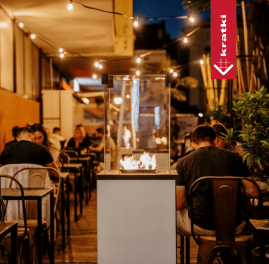 Kratki PATIO Slim gasgestookte terrasverwarmer met echt vuur op een restaurantterras in de avond
