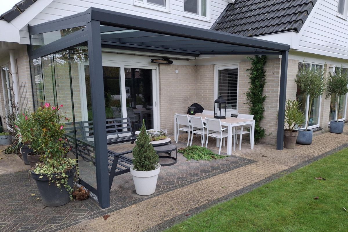 Zijaanzicht van een moderne aluminium veranda van YARD Outdoor met een glazen dak en geïntegreerde glazen schuifdeuren, perfect voor een flexibele en stijlvolle buitenruimte.