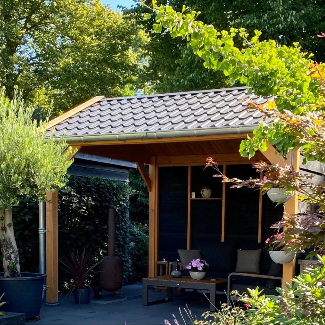 Compacte Douglas kapschuur met dakpannen en zwarte achterwand in een groene tuin