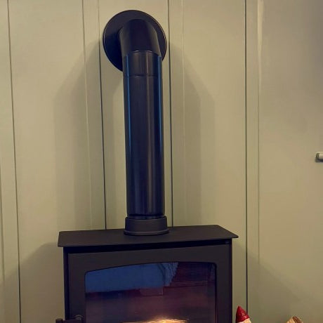 Decoratieve zwarte kachelpijp met bocht van 90° naar de muur op een Ecosy bio-ethanol kachel