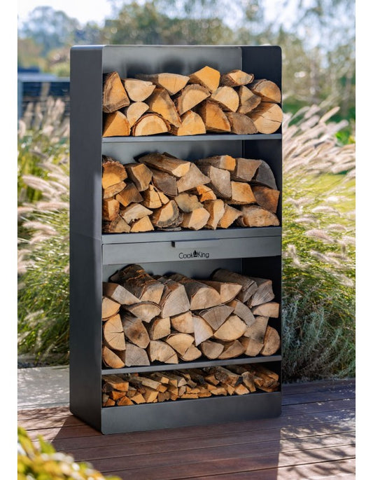 CookKing haardhoutrek VENTO 150 x 80 x 30 cm van zwart staal, gevuld met brandhout op een terras