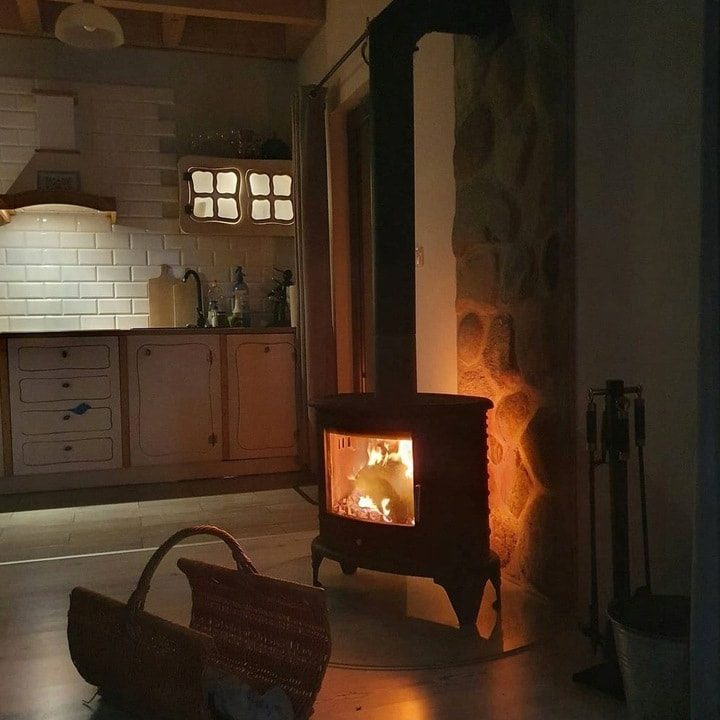 Kratki KOZA K8 houtkachel in een woonkamer tegen de wand