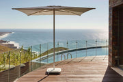 Outdoor parasol Jardinico 230x230 cm in parelwit, stijlvol geplaatst op een modern terras, ideaal voor schaduw en comfort buiten.