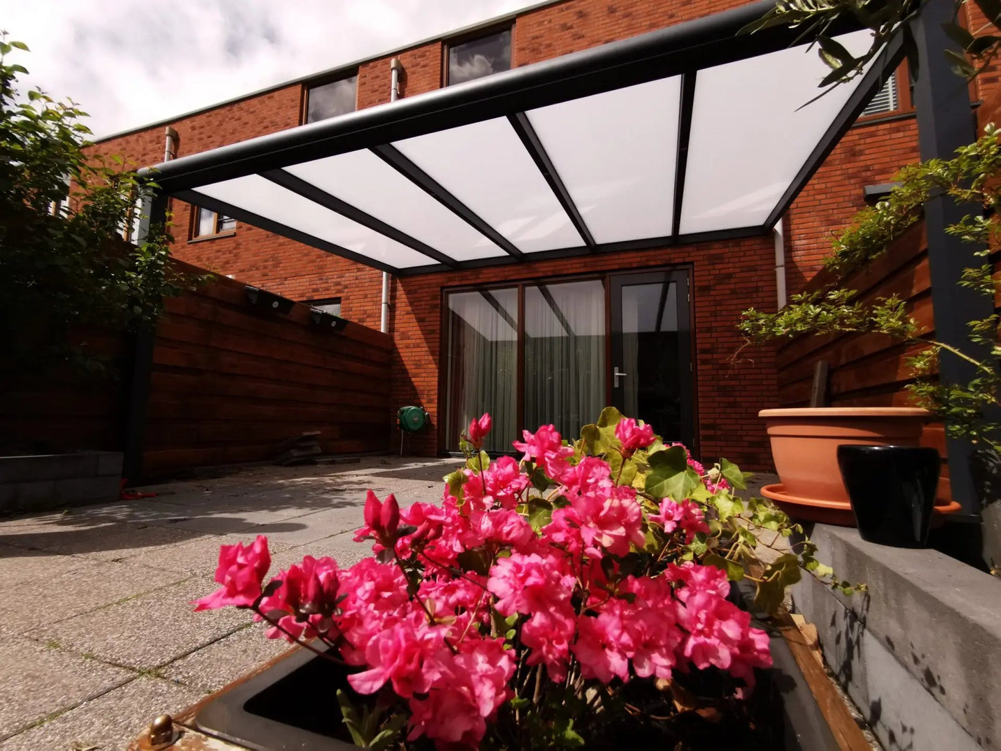 Doorkijk onder de veranda met aluminium frame en diffuus opaal dak voor zachte lichtinval